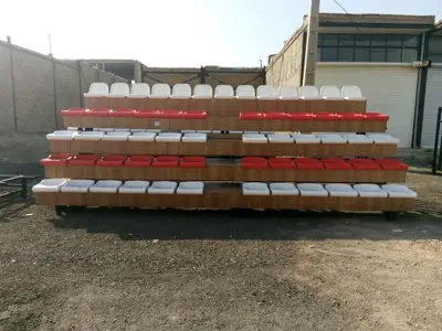نیمکت فوتبال، سکوی چهارردیفه سفید با صندلی‌های قرمز در محوطه صنعتی