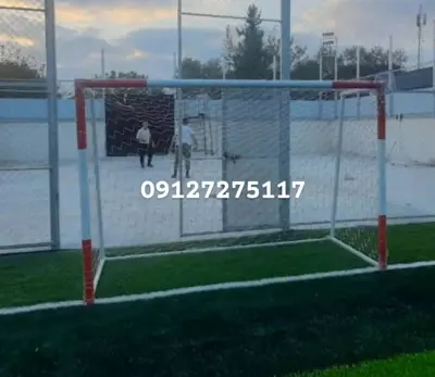 دروازه فوتبال سفید و قرمز نصب شده در زمین چمن مصنوعی