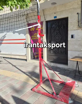 پایه تور والیبال قرمز با مخزن وزنه مستطیلی در پیاده رو - تصویر اصلی