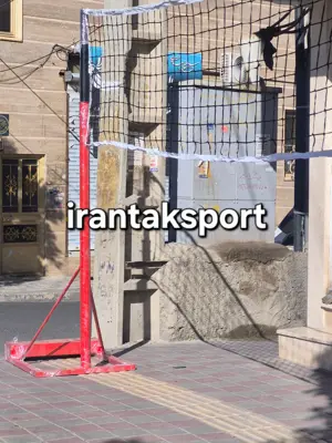 نمای پایه قرمز تور والیبال و سازوکار تنظیم ارتفاع کنار دیوار