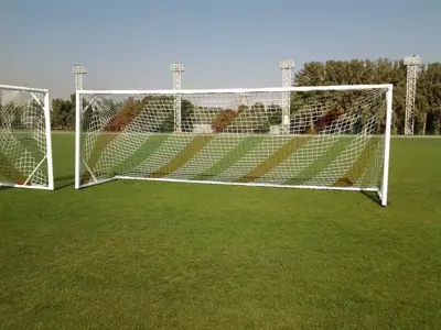 دروازه فوتبال، نمای کناری دروازه سفید و تور روی چمن مصنوعی